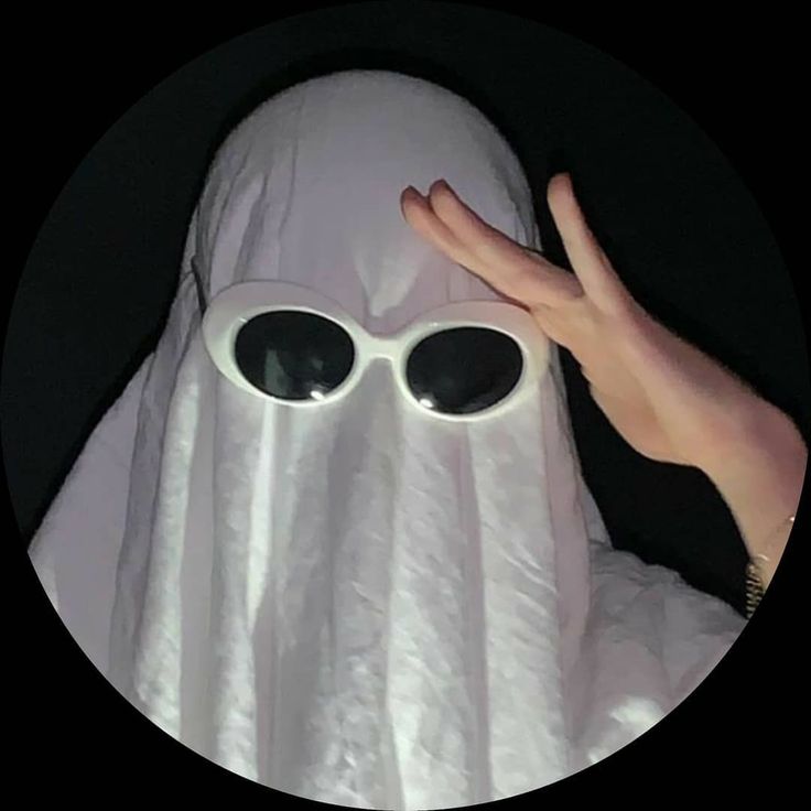 a person in a ghost costume holding their hand up to the camera with two large round sunglasses on it's face