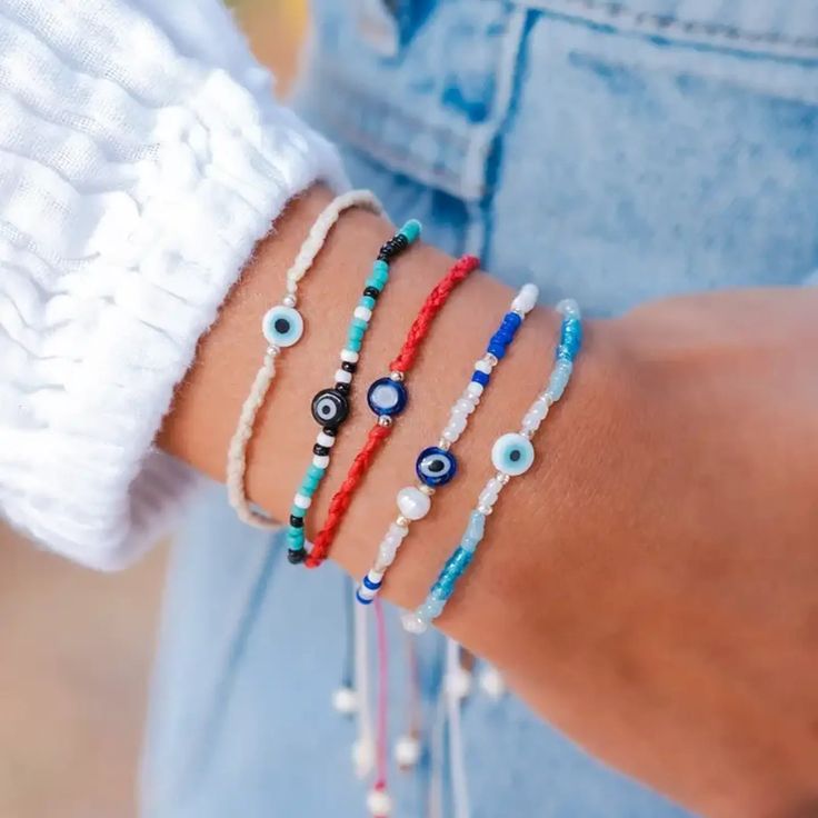 The Beaded Evil Eye Bracelet is more than just a piece of jewelry. With its ancient protective symbol and blue beads, it helps promote peace, confidence, and clarity. Say goodbye to bad omens and hello to a stylish and positive accessory. This stunning Beaded Evil Eye Bracelet features blue, white and cream colored beads with a translucent Evil Eye bead in the center. This Beaded Evil Eye Bracelet features an adjustable size cotton cord fitting wrists sizes from 6.5 - 8.5". Elevate your look and Blue Spiritual Braided Bracelets Hand-strung, Blue Handmade Friendship Bracelet For Healing, Handmade Blue Friendship Bracelet, Bohemian Friendship Bracelets With Evil Eye, Bohemian Braided Bracelet With Evil Eye For Friendship, Bohemian Blue Friendship Bracelets With 8mm Beads, Symbolic Hand-strung Adjustable Beaded Bracelets, Blue Spiritual Friendship Bracelets For Festivals, Spiritual Blue Friendship Bracelets For Festivals