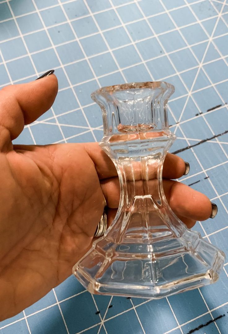 a person holding a clear glass vase on top of a blue tile flooring area