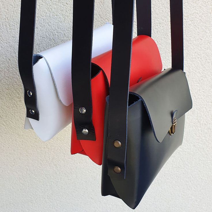 three purses hanging from hooks on a wall