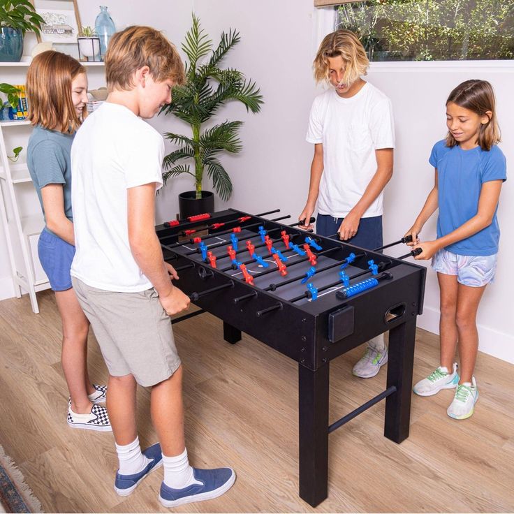 three children and an adult playing a game of foo - pong in the living room