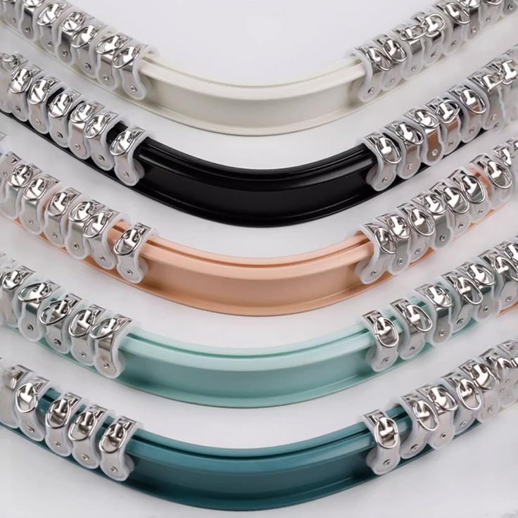 four different colored and metal bracelets are shown in this image, one is black, the other is white