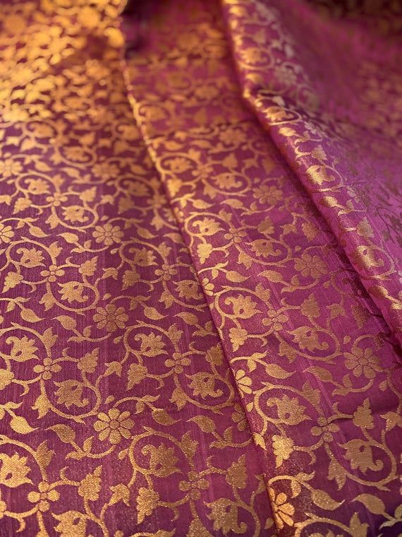 This listing is for 1 yard of beautiful purple golden brocade silk. Fabric Width: 42-43” wideFabric Type: Semi Silk BrocadeThroughout history, brocade was a fabric of luxury worn by nobility in various cultures, from India to Korea. Brocade is a heavy fabric similar to jacquard with a raised pattern or floral design. Traditionally the pattern was produced with gold or silver thread said to be of such superb quality that they could be woven into the fabric of gold and silver. Elegant Brocade Dupatta With Woven Motifs, Traditional Festive Jacquard Fabric, Gold Brocade Dupatta With Woven Motifs, Elegant Gold Traditional Wear With Woven Motifs, Elegant Brocade Saree With Woven Motifs, Brocade Fabric With Zari Weaving For Festivals, Elegant Brocade Blouse Piece With Motifs, Traditional Gold Fabric With Traditional Patterns, Elegant Brocade Fabric With Traditional Embroidery