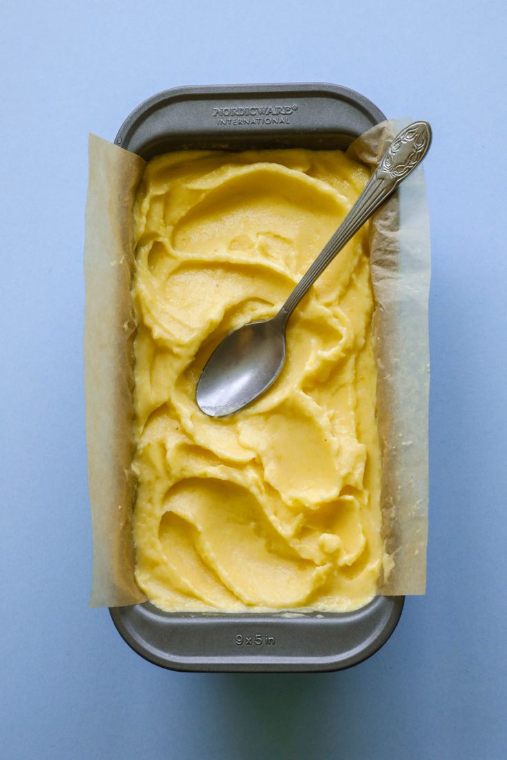 a spoon in a container filled with ice cream on top of a blue tablecloth