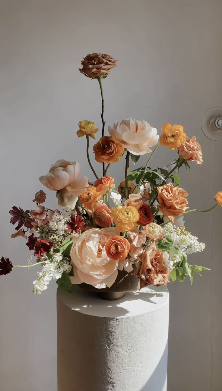 a white cake topped with lots of different colored flowers on top of a wooden table