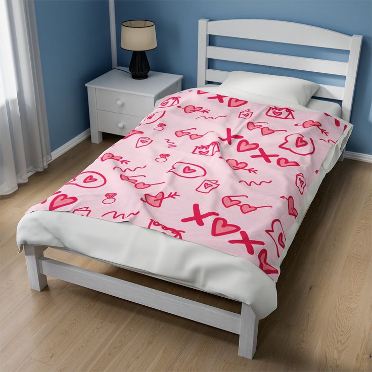 a bed with pink hearts on it in a blue room next to a white nightstand