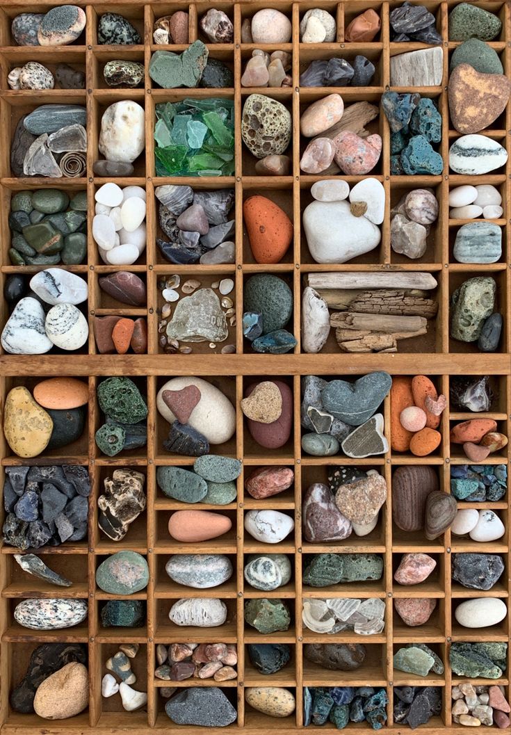 many different rocks are arranged in a wooden box with dividers on the bottom and sides