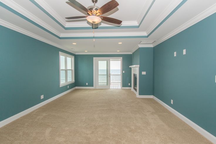 an empty room with blue walls and ceiling fan