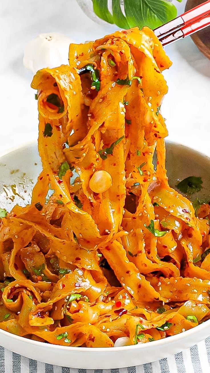 a bowl full of noodles with chopsticks sticking out of the top and another dish in the background