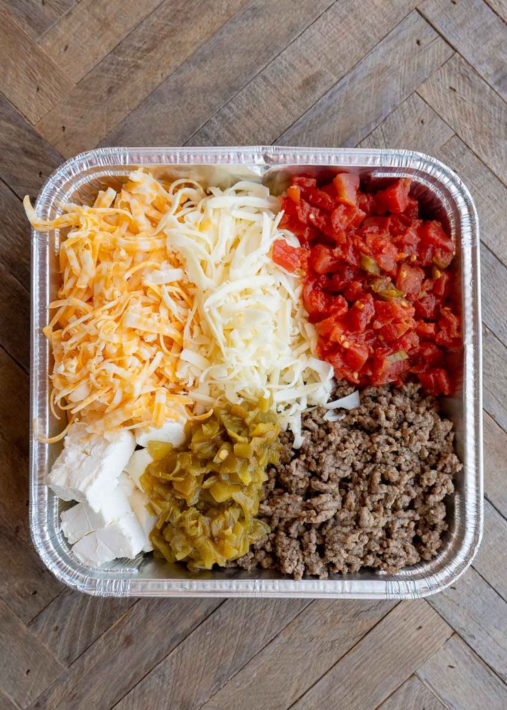 a plastic container filled with lots of different types of food on top of a wooden table