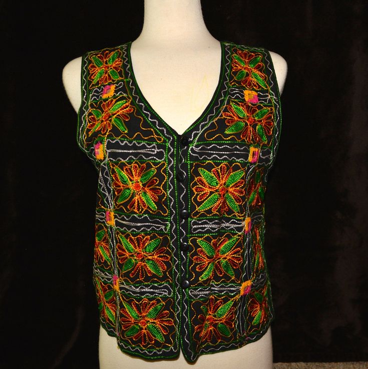 This vest is an embroidered vest with floral pattern and small mirrors woven into it. It reminds me of an El Matador vest Would work great for an ugly Christmas sweater party or for a Halloween costume, Mardi Gras or just getting back to your roots! DETAILS Condition: Good MEASUREMENTS Size on tag: Women's Large could work for men also Back of neck to Bottom: 19.5" Armpit to Armpit: 18.5" All measurements are taken flat across garment. For most accurate size please double check measurements against one of your own garments. Vintage sizes vary from modern sizes.  I am happy to provide any other measurements you need - just ask!! This item is pre-worn but is in good condition.  Any piling or imperfections are part of the charm and character of the item and should be taken into consideration Winter Floral Embroidered Sleeveless Vest, Embroidered Festival Vest, Festive Fitted Vest With Floral Embroidery, Embroidered Sleeveless Vest For Festival, Fitted Vest With Floral Embroidery For Festive Season, Multicolor Vest Tank Top For Festival, Embroidered Sleeveless Party Top, Sleeveless Top With Multicolor Embroidery For Party, Sleeveless Multicolor Embroidered Top For Party