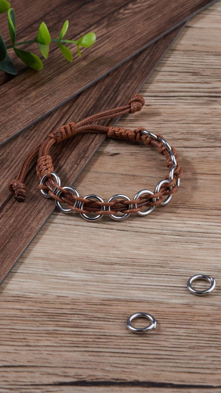 two silver rings are sitting on a wooden table next to some other metal objects and greenery