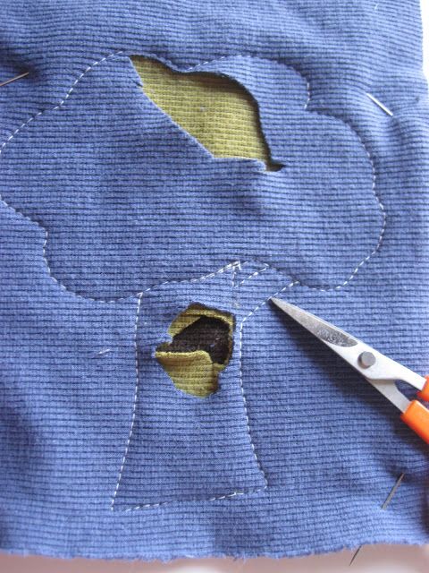 someone is cutting through the hole in their blue fabric to make a flower design with scissors