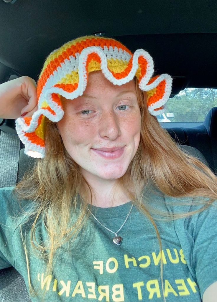 a young woman wearing a crocheted hat in the back seat of a car