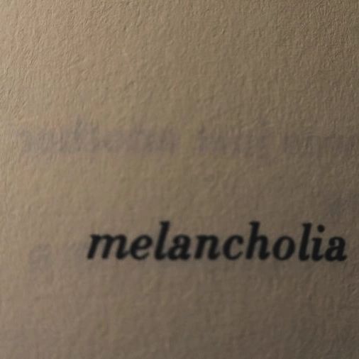 the word melancholia written in black ink on a piece of white paper