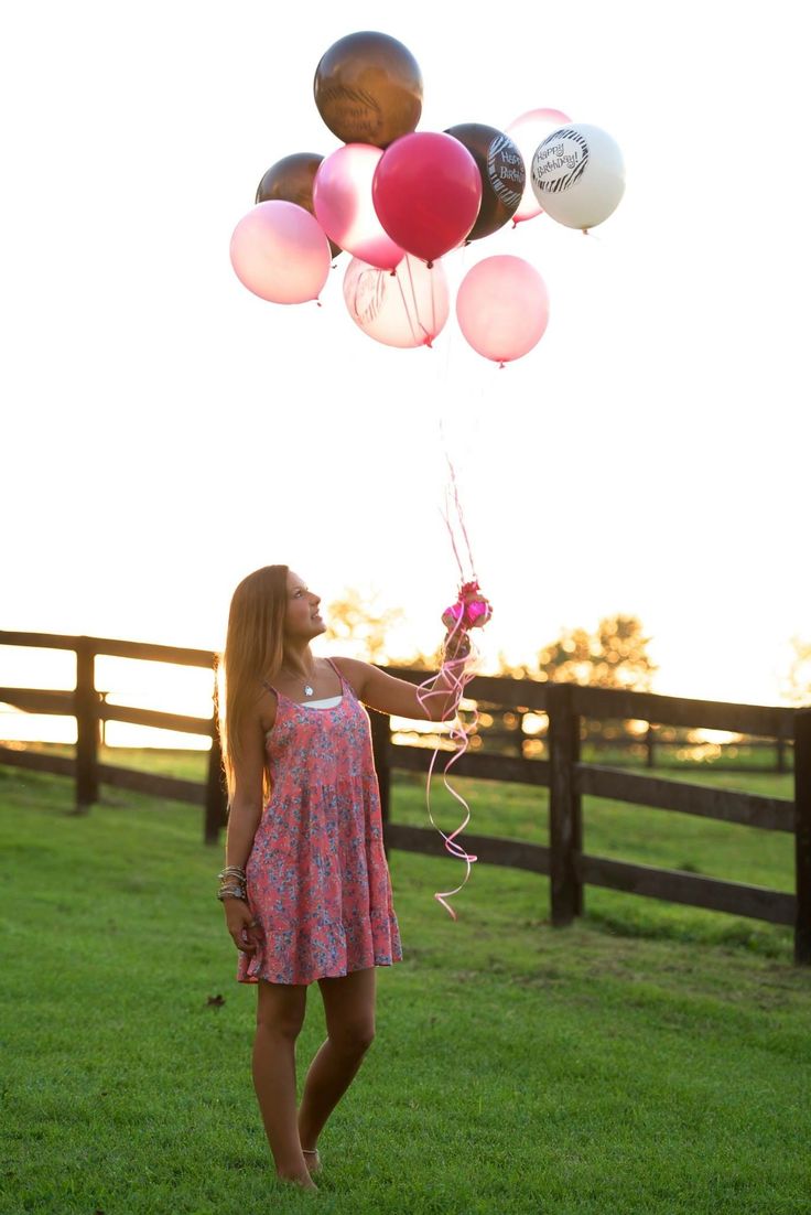 a woman in a pink dress is holding some balloons