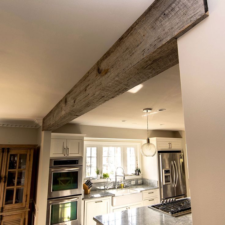 a kitchen with an oven, stove and sink under a wooden beam in the ceiling