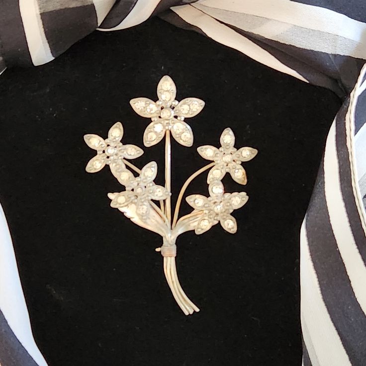 Vintage silver tone floral bouquet brooch. This is a pretty sparkling brooch displaying five stemsfloral of daisies bound by brass colored wire. This would add a big vintage sparkle to your jewerly collection. This is the the of piece that you can wear to any occasion.  It is in an good pre-loved vintage condition some patina and minor age wear. All rhinestones are present and intact.   Measures approximately 3.5" tall and  2.5" wide. Has fold over clasp pin. Please refer to pictures for your ac Flower Shaped Costume Jewelry Brooches For Wedding, Silver Flower Brooches With Flower Decoration, Silver Flower Brooch With Flower Decoration, Silver Flower Brooch With Floral Decoration, Silver Flower Shaped Brooch With Floral Decoration, Silver Rhinestone Brooch For Vintage Events, Brooch Display, Bouquet Brooch, Gold Flower-shaped Brooches With Rhinestones