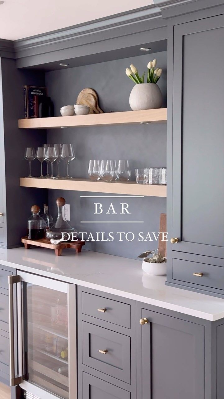 a kitchen with gray cabinets and shelves filled with wine glasses, champagne flutes, and flowers