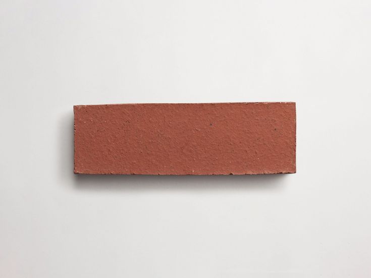 a piece of red brick sitting on top of a white surface