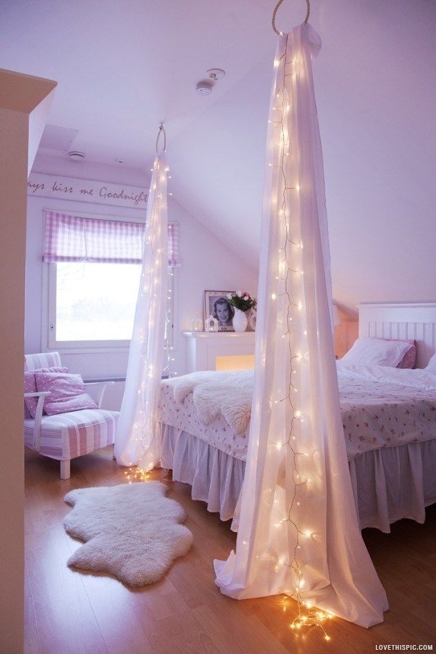 a bedroom with white bedding and lights on the ceiling