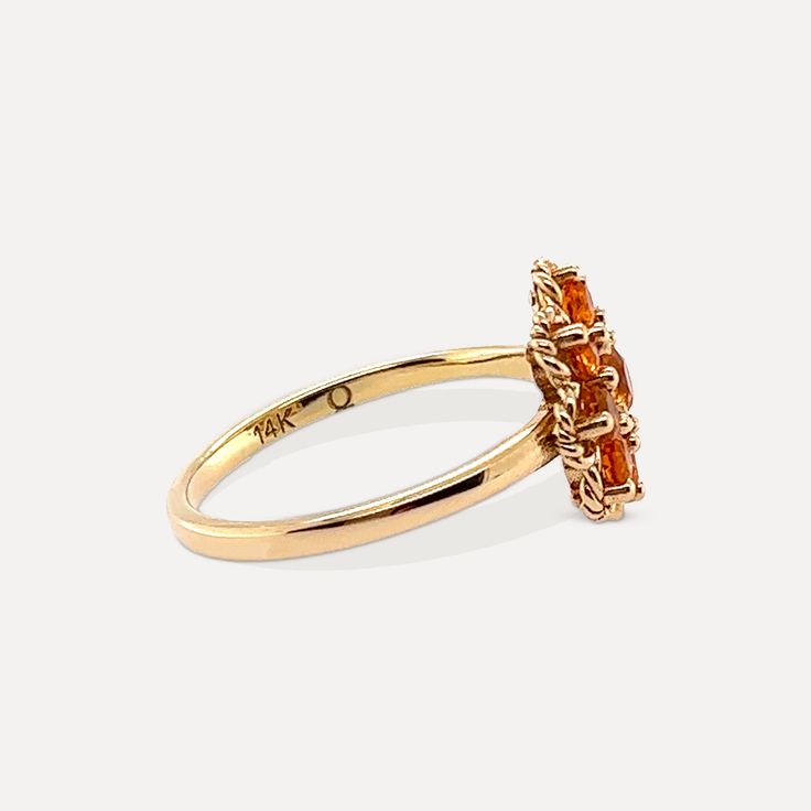 a gold ring with an orange stone in the center and two smaller stones on each side