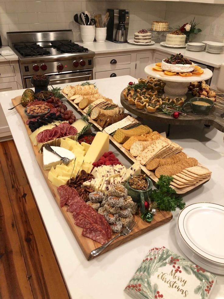 an assortment of cheeses, meats and crackers on a table in a kitchen