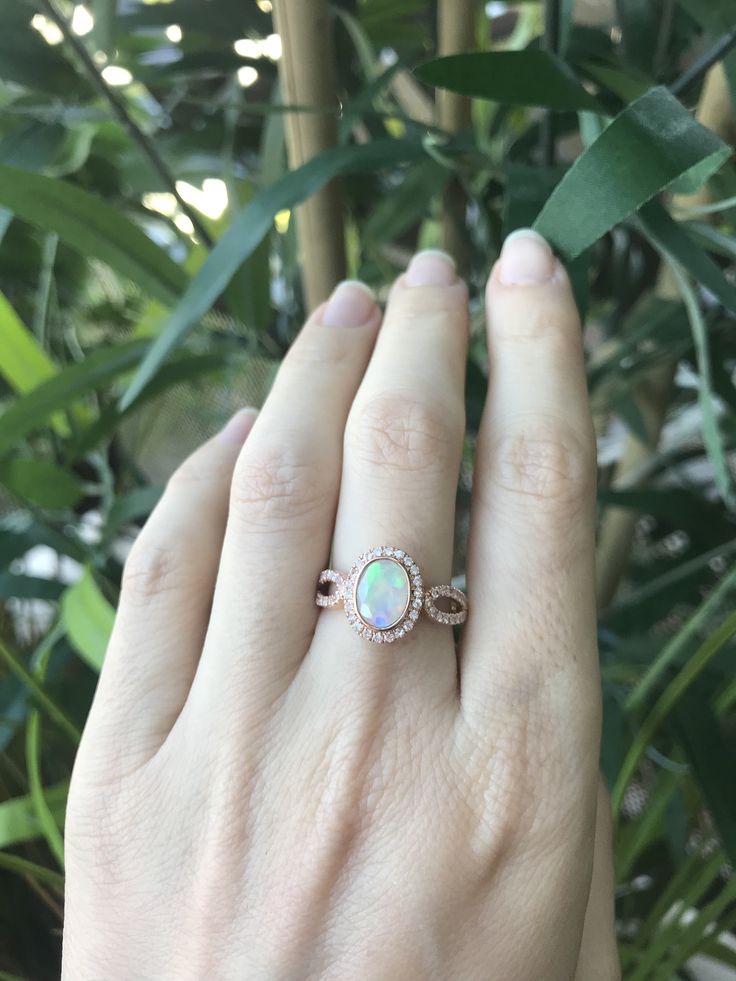 "An oval-shaped natural and genuine Opal set in a bezel setting accented with petite white sapphires handcrafted in your choice of 10k/14k/18k Rose/Yellow Gold or White Gold. This ring makes a lovely engagement/promise/October birthstone/statement ring. Wrapped in a Box ready for gift giving.(r-egt-20) Please note each opal has a unique play of color, if you wish for a certain color in the fire, please let us know and we will try to accommodate your request. View our Instagram video of this Ring Oval Halo Jewelry For Anniversary, Oval Rose Gold Opal Gemstone Ring, Oval Cubic Zirconia Birthstone Ring Gift, Oval Diamond White Jewelry With Birthstone, Rose Gold Oval Opal Gemstone Ring, Diamond White Oval Jewelry With Birthstone, Rose Gold Oval Opal Ring, Oval Halo Design Jewelry For Anniversary, Diamond Oval Birthstone Ring As A Gift