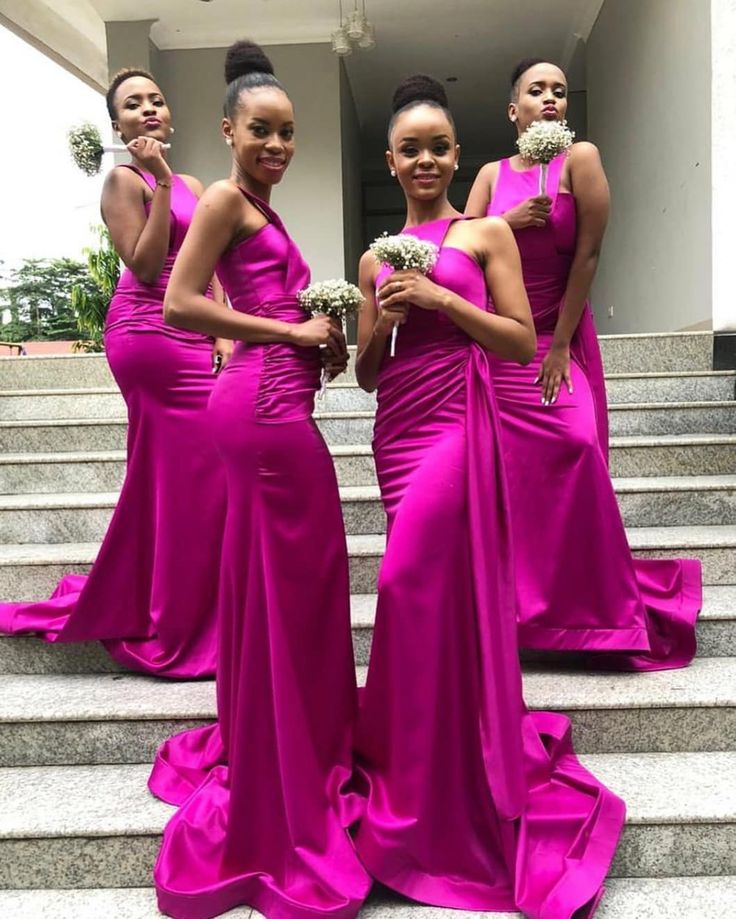 three women in bright pink dresses standing on steps with their hands together and one is holding flowers