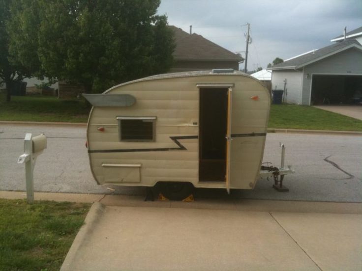 an old trailer is parked on the side of the road next to a parking meter