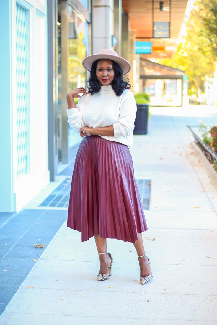 Pleated faux leather skirt with asymmetrical hemline. Pairs well with both fitted bodysuits and chunky sweaters. Styled here with our Sophia sweater and Sandy hat. Fabric: 55% PU, 45% Polyester Model is 5'6 and wearing a size medium. Red Pleated Skirt Outfit, Maroon Skirt Outfit, Pleated Leather Skirt Outfit, How To Style Pleated Skirt, Burgundy Skirt Outfit, Pleated Midi Skirt Outfit, Pleated Skirt Outfits, Pleated Skirt Plus Size, Maroon Outfit