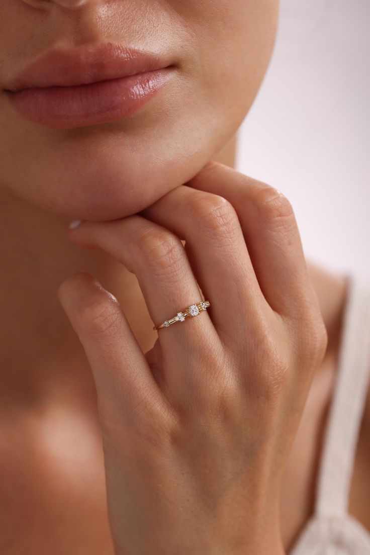 a woman wearing a diamond ring with her hand on her chin looking at the camera