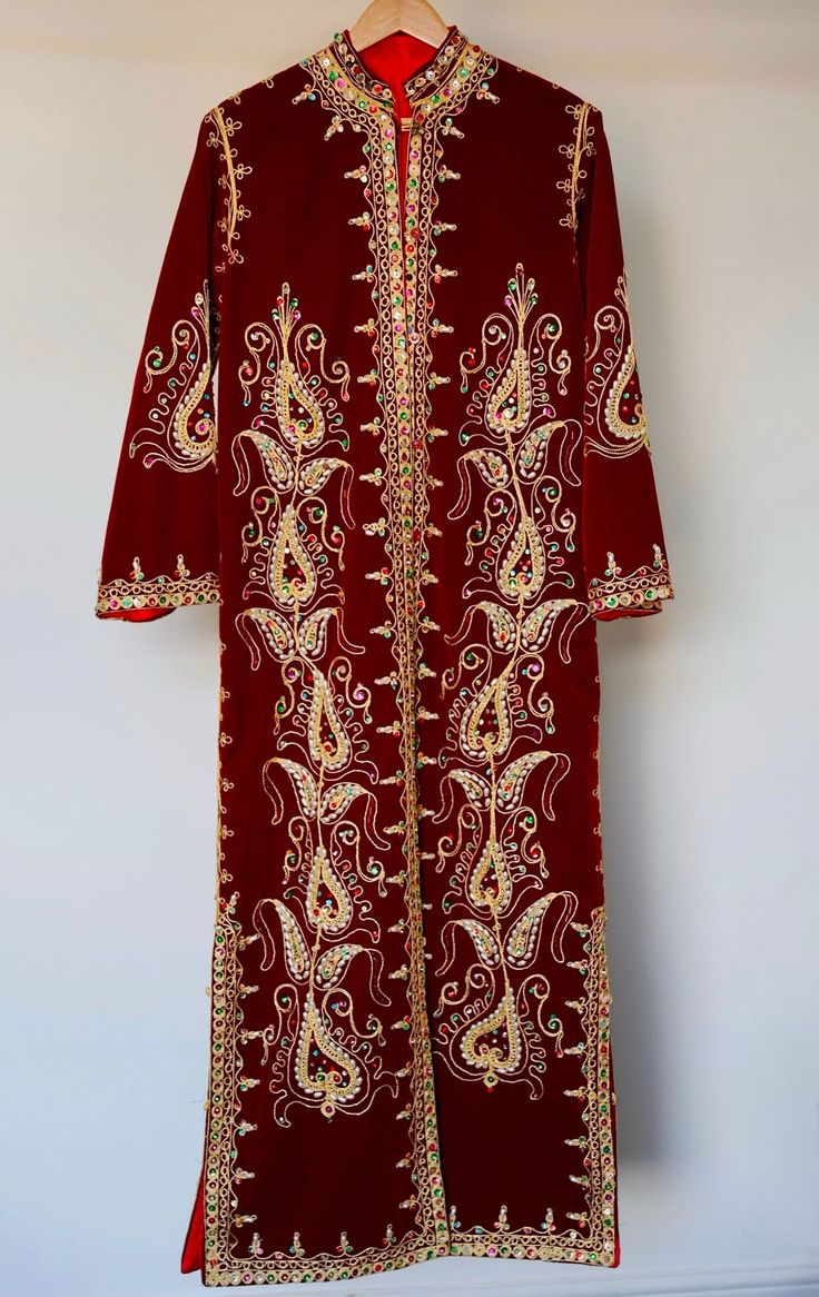 Your 1970s caftan dress represents a timeless piece of elegance, skillfully blending oriental tradition with vintage refinement. Its elaborate manual embroideries, crafted with golden thread, semi-precious pearls, and delicate sequins, showcase the exceptional craftsmanship of its time. Every detail reflects the artisanal mastery of that era, highlighting the passion and devotion of the creators behind this sartorial masterpiece. The dress's pristine condition, preserved like new, serves as evidence of meticulous care throughout the decades. More than just a garment, it becomes a chronicle of timeless elegance and the tradition of beauty. It carries not only the history of fashion but also the imprint of an era where textile art and intricate details reached their zenith. Dimensions: 40 in Festival Maxi Dress With Resham Embroidery For Traditional Ceremonies, Ceremonial Long Sleeve Eid Dresses, Traditional Long Dresses For Transitional Season, Ceremonial Long Sleeve Dresses For Eid, Long Dresses For Traditional Ceremonies, Traditional Maxi Dress With Intricate Embroidery For Ceremonies, Ceremonial Long Sleeve Dress With Resham Embroidery, Elegant Dress With Multicolor Embroidery And Traditional Drape, Ceremonial Long Sleeve Festive Dress