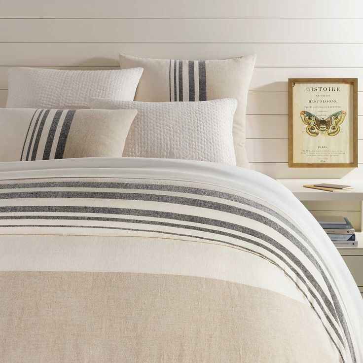 a bed with black and white striped comforter next to a framed painting on the wall