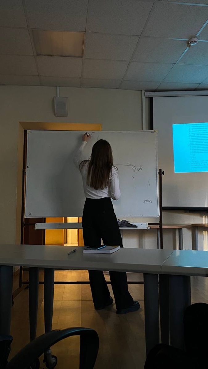 a woman standing in front of a whiteboard while giving a presentation to someone else