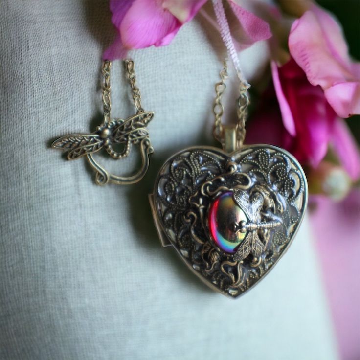 "Dragonfly music box pendant. This heart shaped music box pendant is inspired by the gorgeous music box pendants of era's gone by. Music box is pill box size, please look at the dimensions for exact size.  A perfect heart locket in bronze has been adorned with a layer of bronze filigree topped with a calla lily stamping. Nestled in the center of the calla lily is a ruby glass cabochon with an iridescent finish. A delicate dragonfly sits on the edge of the glass cabochon.  Calla lily, dragonfly and filigree have been covered in a clear resin to give a glass like finish and preserve the beauty of this musical pendant.  Choose the music box tune you would like at checkout.To listen to the music box tunes, get more information on our music boxes and see our limited addition tune list, go to ht Victorian Heart Pendant Necklace Keepsake, Victorian Heart Pendant Necklace For Keepsake, Vintage Round Pendant Locket Necklace For Valentine's Day, Vintage Locket Necklace For Valentine's Day, Elegant Heart Locket Necklace Collectible, Victorian Heart-shaped Necklace For Gift, Vintage Round Locket Necklace For Valentine's Day, Vintage Valentine's Day Locket Necklace With Round Pendant, Elegant Heart Locket Necklace For Collectors