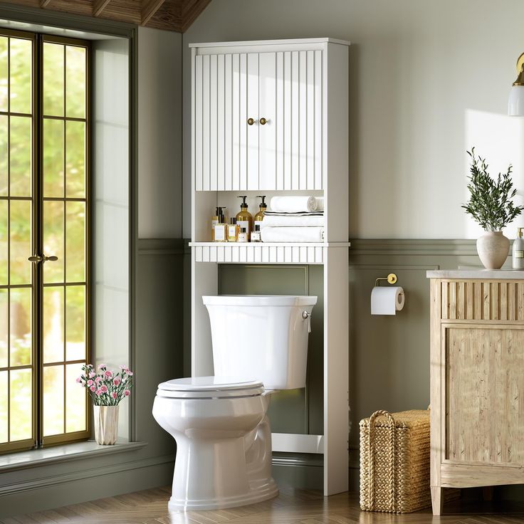 a white toilet sitting in a bathroom next to a wooden cabinet and window sill