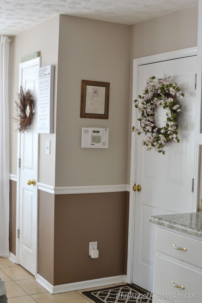 the interior of a house with white and brown walls, wreaths on the door