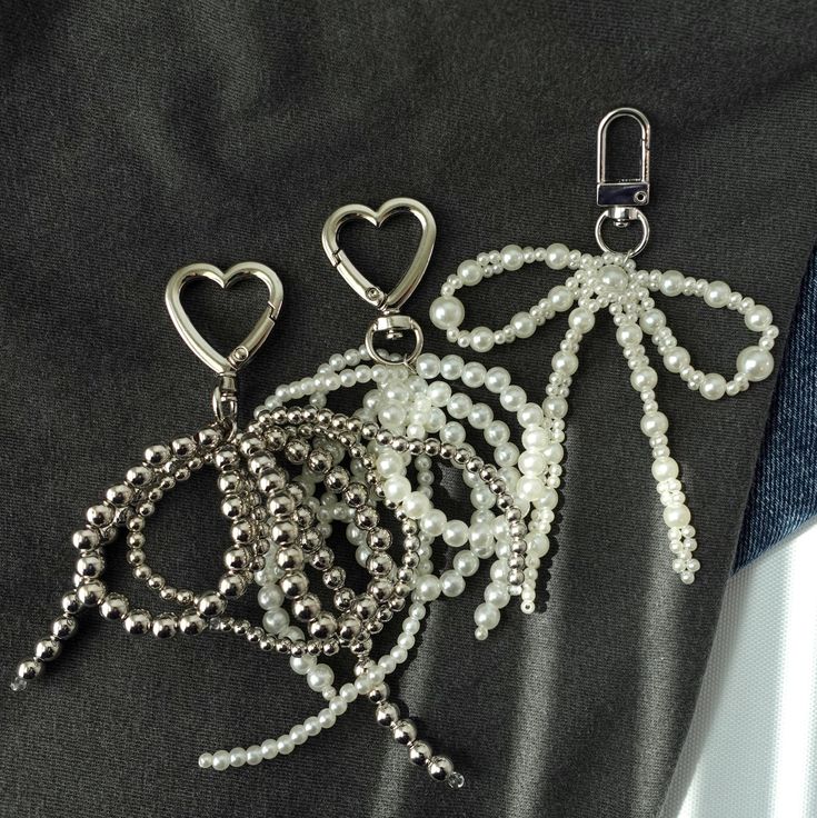 three different types of beaded key chains on a black cloth with heart shaped charms attached to them