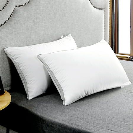 two white pillows are on top of a gray bed with beaded headboard and night stand