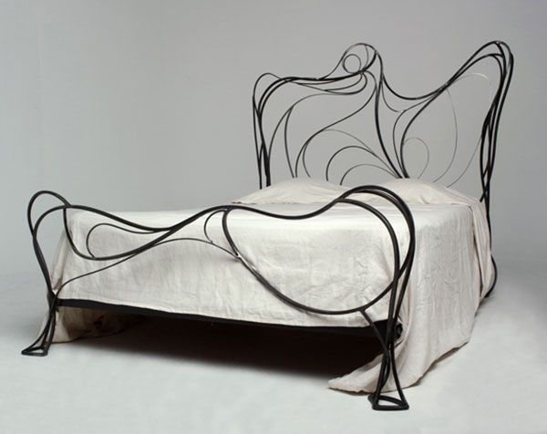 an iron bed with white sheets and black metal headboard is shown against a gray background