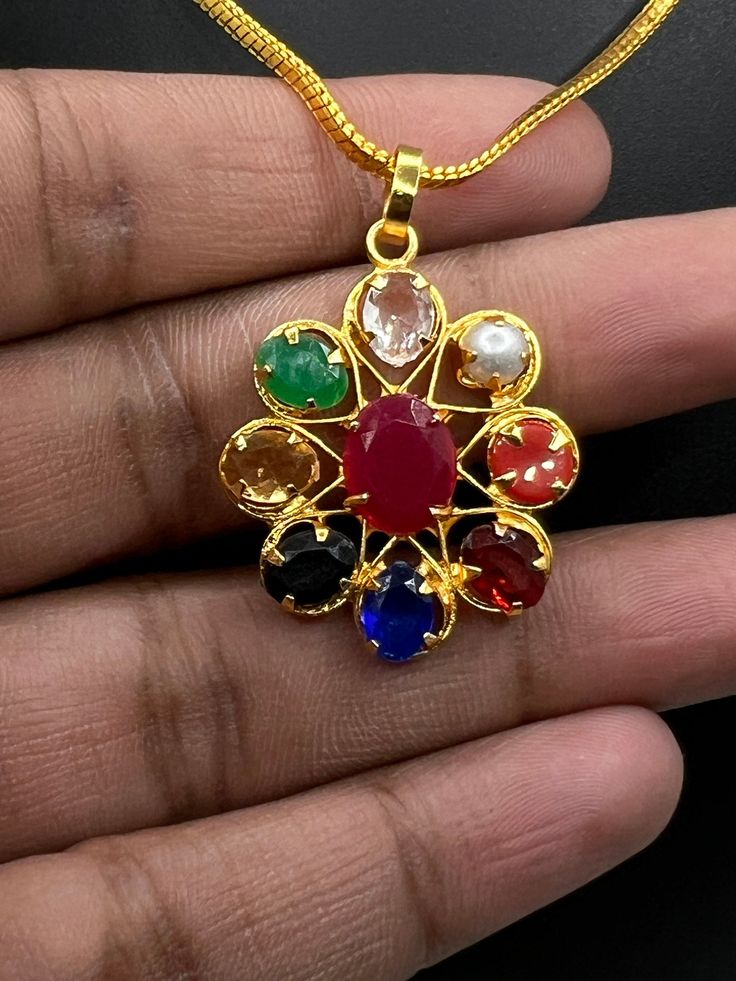 Discover the timeless beauty and positive energies of our Exquisite Navratna Pendant. This handcrafted masterpiece features a collection of nine vibrant semi-precious gemstones set in a base of high-quality brass. Each stone represents a celestial body, making this pendant not only a stunning piece of jewelry but also a powerful talisman for spiritual harmony and positive energy. Key Features: Nine Gemstones: The pendant showcases the brilliance of nine semi-precious gemstones, each carefully chosen for its unique color and metaphysical properties.  Semi-Precious Stones: All the gemstones used in this pendant are semi-precious, selected for their beauty, symbolism, and positive energies. They bring together the healing properties of different stones in one harmonious piece. Handcrafted Ele Multicolor Spiritual Jewelry With Stone Setting, Traditional Multi-stone Gemstones As Gift, Traditional Multi-stone Gemstones For Gifts, Spiritual Gemstone Necklace For Puja, Traditional Natural Gemstones As Gifts, Handmade Multicolor Gemstones Gift, Multicolor Gemstone Oval Pendant Jewelry, Multicolor Oval Pendant Gemstone Jewelry, Multicolor Gemstones With Stone Setting As Gift