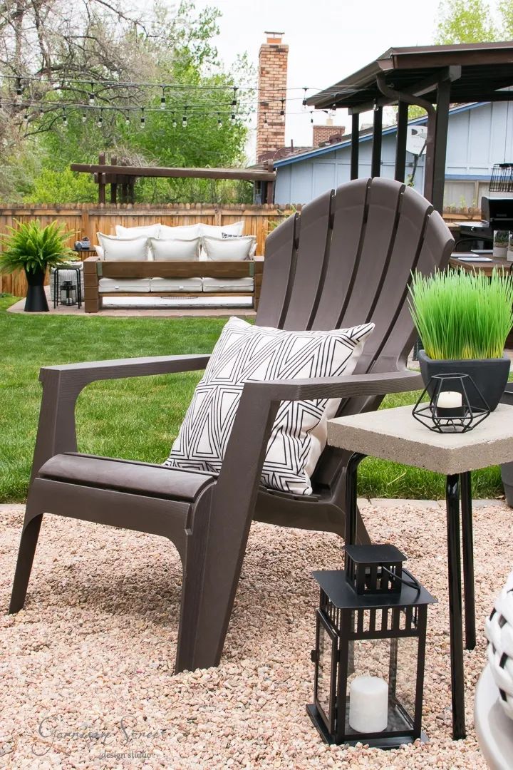 a patio with chairs, table and potted grass in the center on gravel area