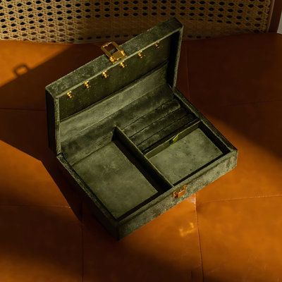 an open green box sitting on top of a brown floor next to a chair and wall