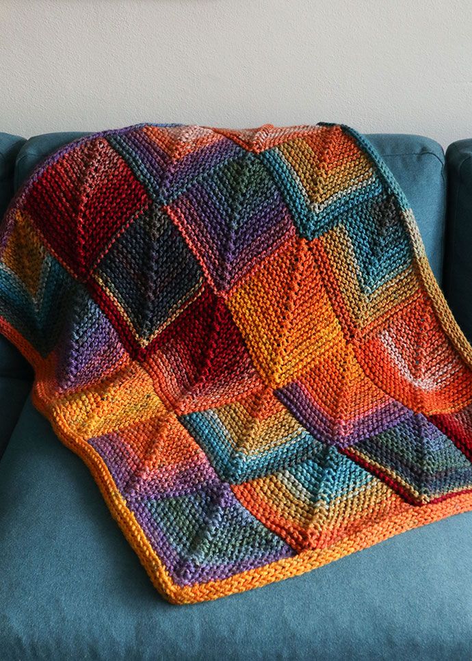 a multicolored crocheted blanket sitting on top of a blue couch