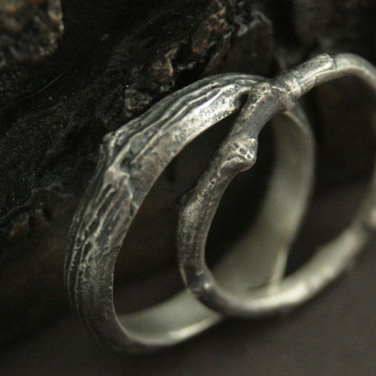 two silver rings sitting on top of a rock