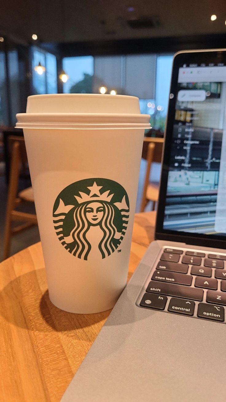 a cup of coffee next to a laptop on a table