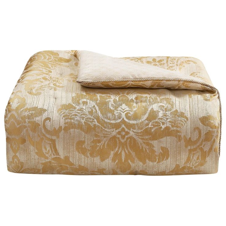 a gold and white comforter set on top of a bed next to a pillow