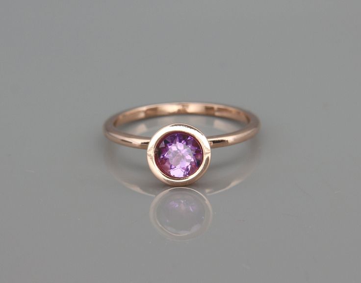 a gold ring with an amethorate stone in the center, sitting on a gray surface