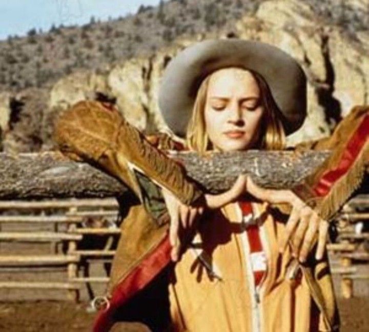 a woman in a cowboy hat holding a large piece of wood with her hands behind her back